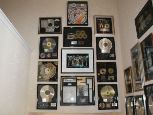 Musician's wall of art and awards in private home installed by professional art installation - Art Hangers