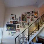 Collage of photos hung orderly along stair wall 