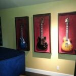 Framed guitars hung on wall with spot light - Art Hangers