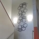 Professional art installation by Art Hangers of metal wall art ascending up the stairs